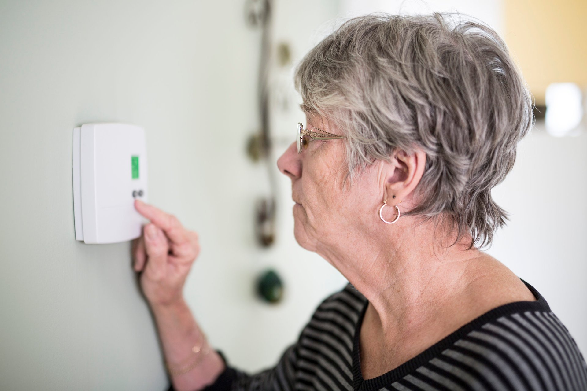 Old woman controlling thermostat