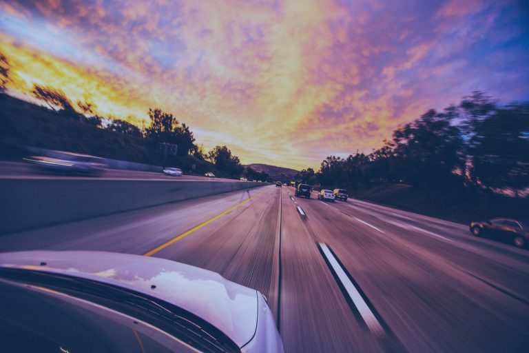 A highway traffic monitoring system collecting traffic data by detecting cars driving down the road at sunset.