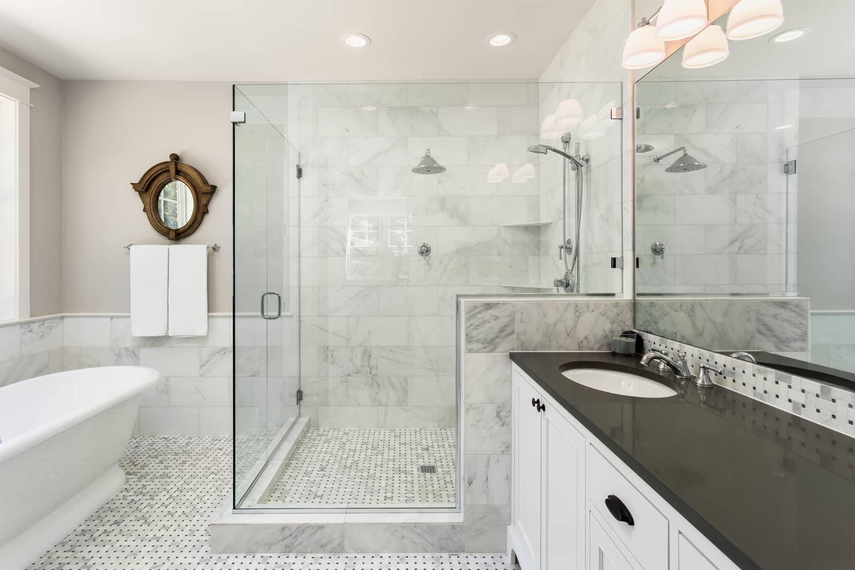 A glass shower with marble tiled walls.