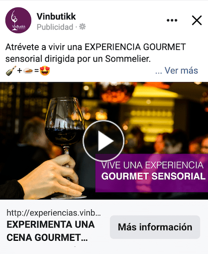 Una persona sosteniendo una copa de vino frente a un anuncio de Facebook.