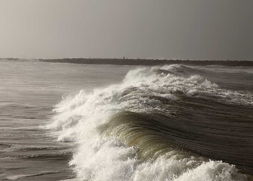 Bølgerne fra nattens storm ruller tungt mod stranden mellem molerne i Hvide Sande