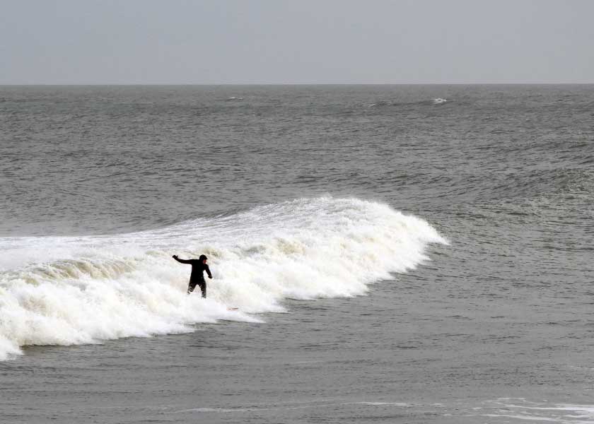 Surferen har efter flere timers ventetid ramt bølgen perfekt og er netop kommet på benene for at styre brædtet mod kysten