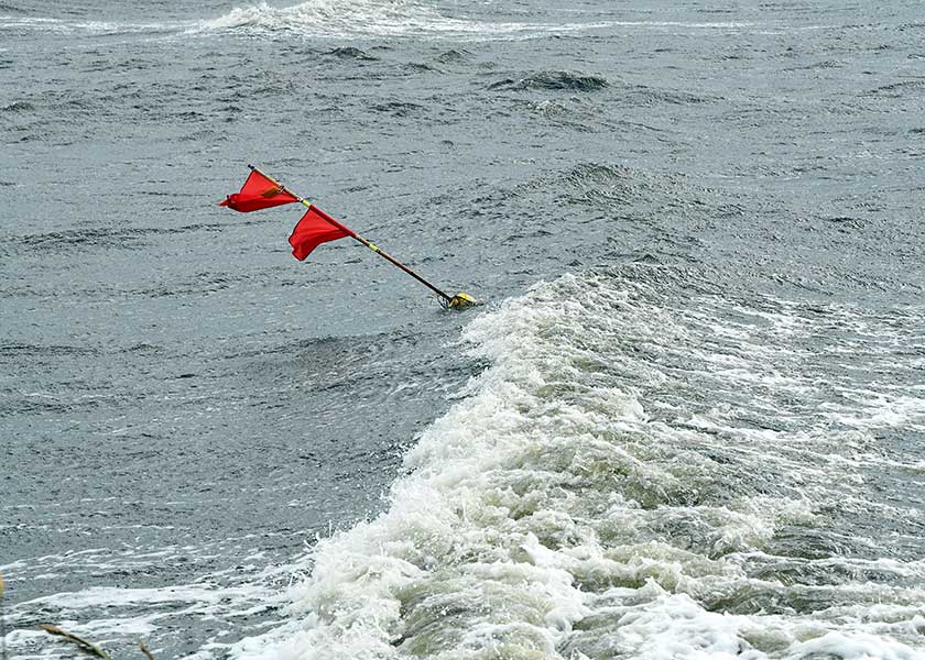 Bøjen som markerer fiskernes garn i fjorden duver let i bølgernes sagte bølgegang