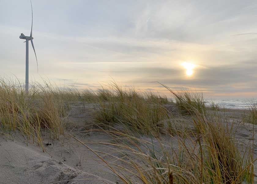En af møllerne på nordstranden i Hvide Sande står som en ensom majestæt og holder øje med solen der er på vej i havet