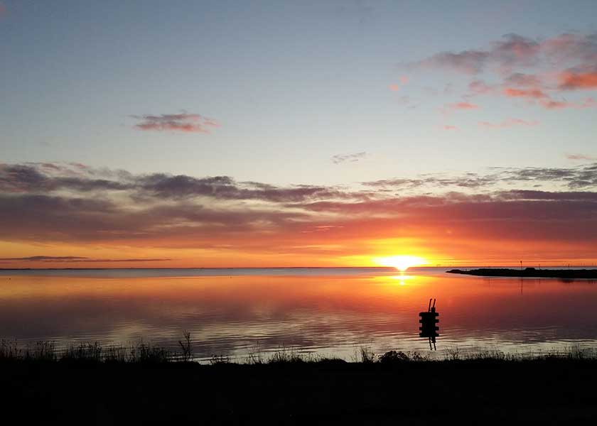 Meget tidlig morgen ved fjorden med udsigten fra afvandingsslusen ved Hvide Sande - solen har lige sluppet vandet og stiger nu mod den blodrøde himmel
