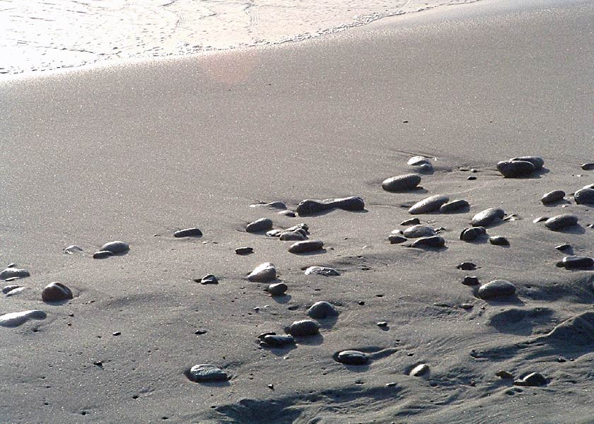 Lyset fra den nedgående sol spiller smukt i stenene på stranden