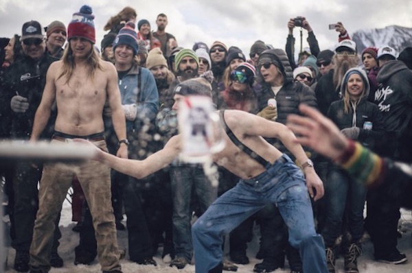 A man is throwing a snowball in front of a crowd, creating the best winter game ever.