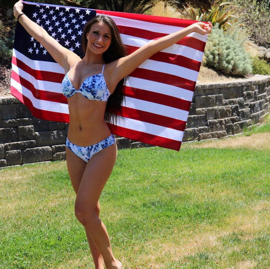 A bikini-clad woman proudly holding an American flag reminiscent of college days.